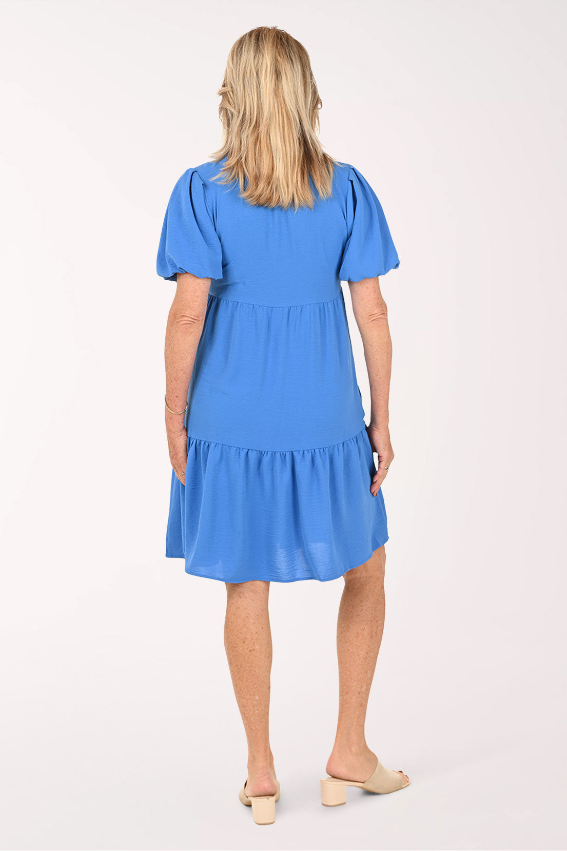 Woman wearing a blue tiered dress with short puff sleeves