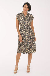 A woman modeling a short-sleeve collared dress with a beige, brown, and black leopard print pattern, paired with beige heeled sandals, against a plain white studio background.