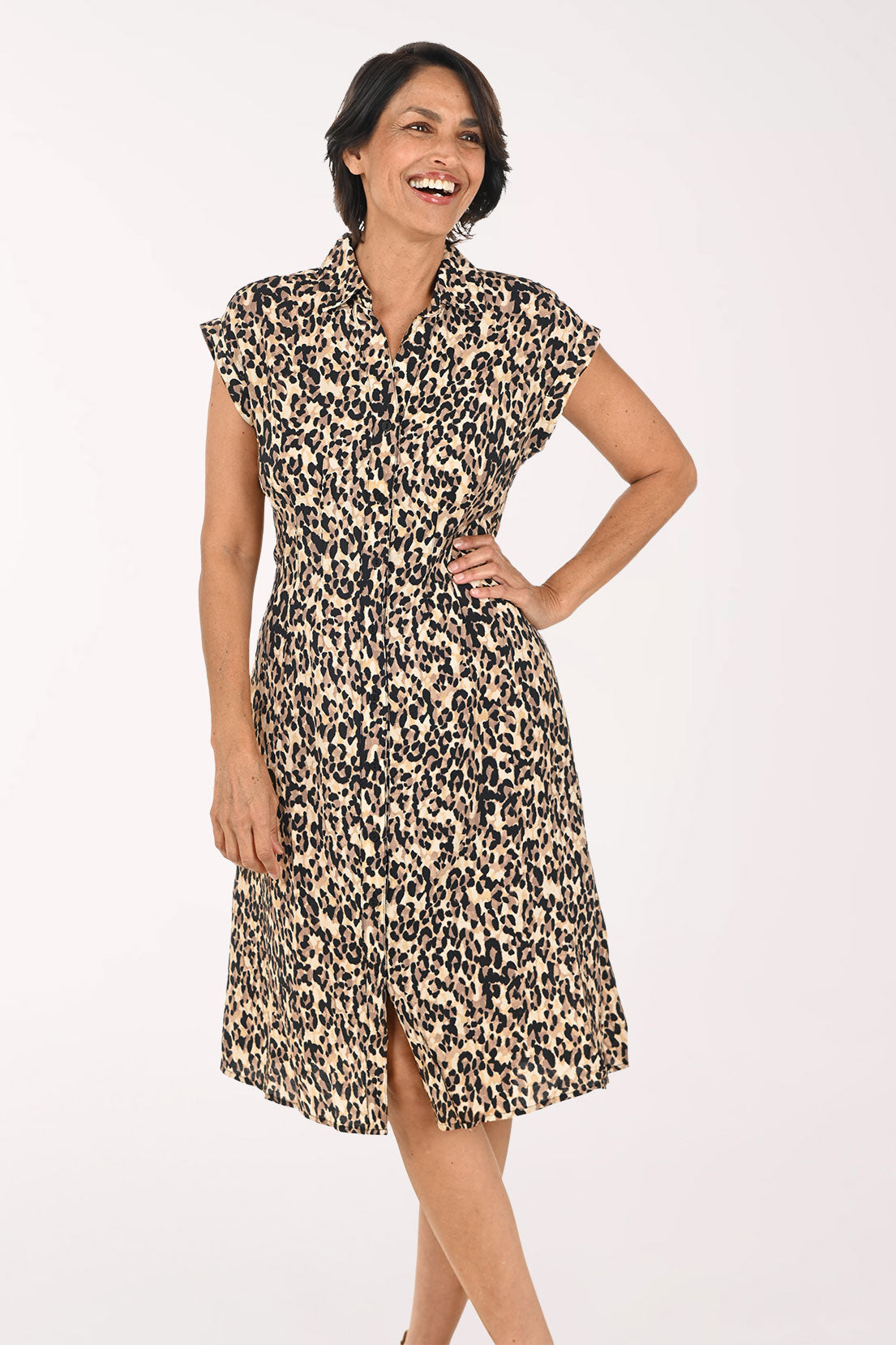 A woman modeling a short-sleeve collared dress with a beige, brown, and black leopard print pattern, paired with beige heeled sandals, against a plain white studio background.