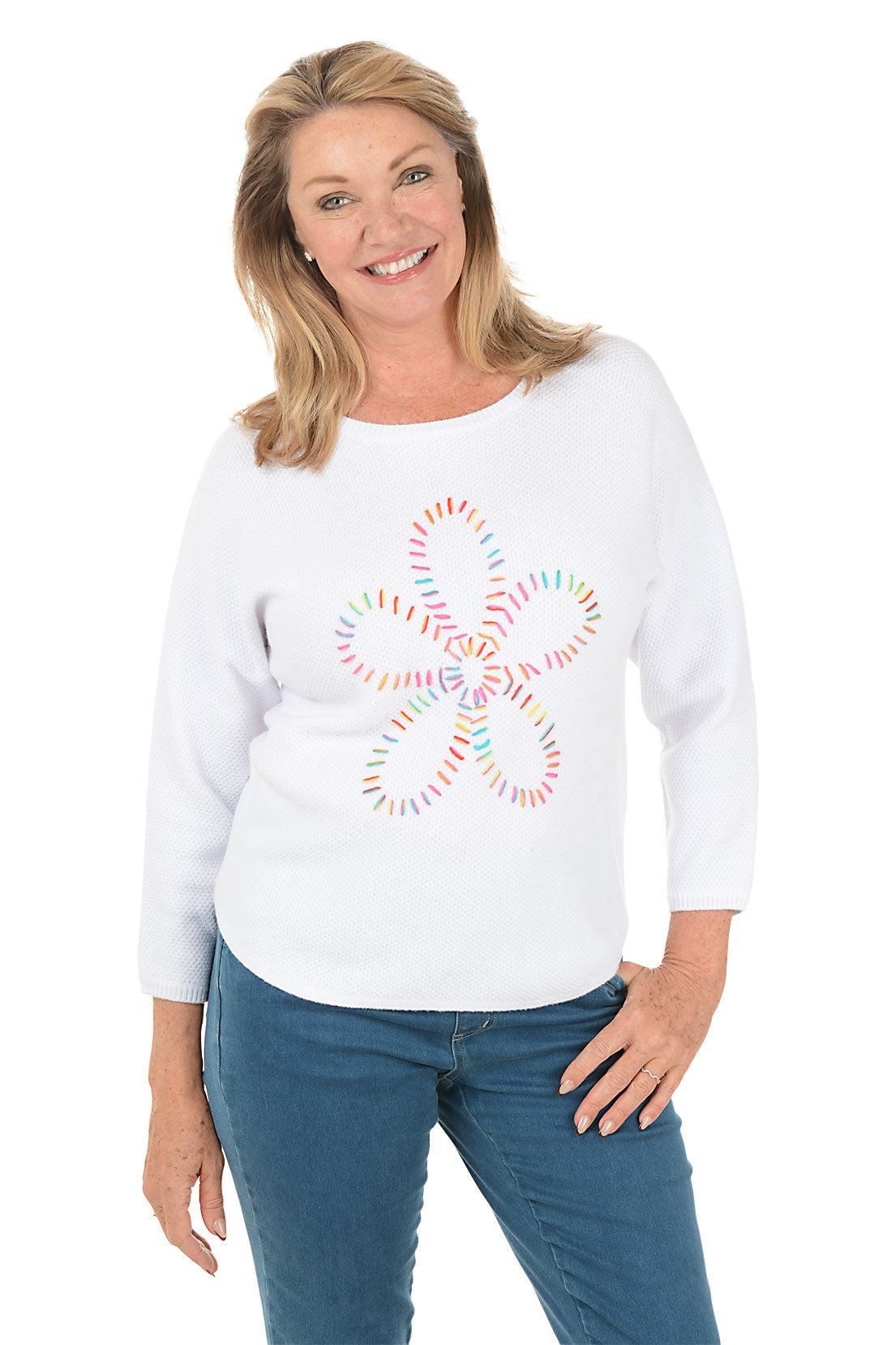 Woman wearing a white sweater with a colorful snowflake design on a white background.