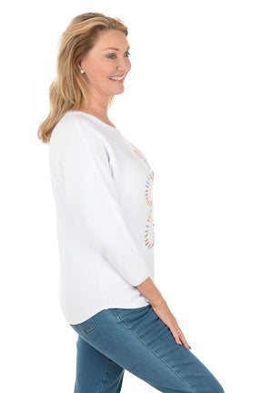 Woman wearing a white sweater with a colorful snowflake design on a white background. Side shot.