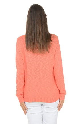 Woman wearing a coral sweater with 'BEACH' text on a white background. Back shot.