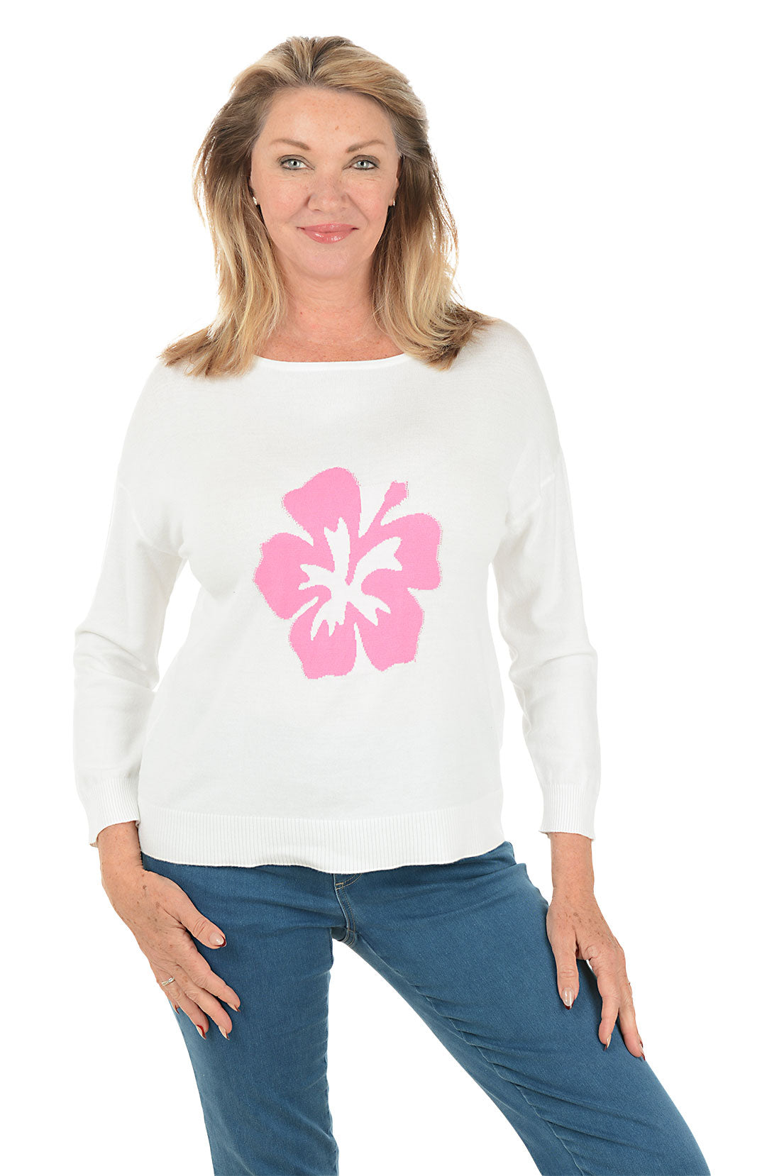 Woman wearing a white sweater with a pink flower design on a white background.