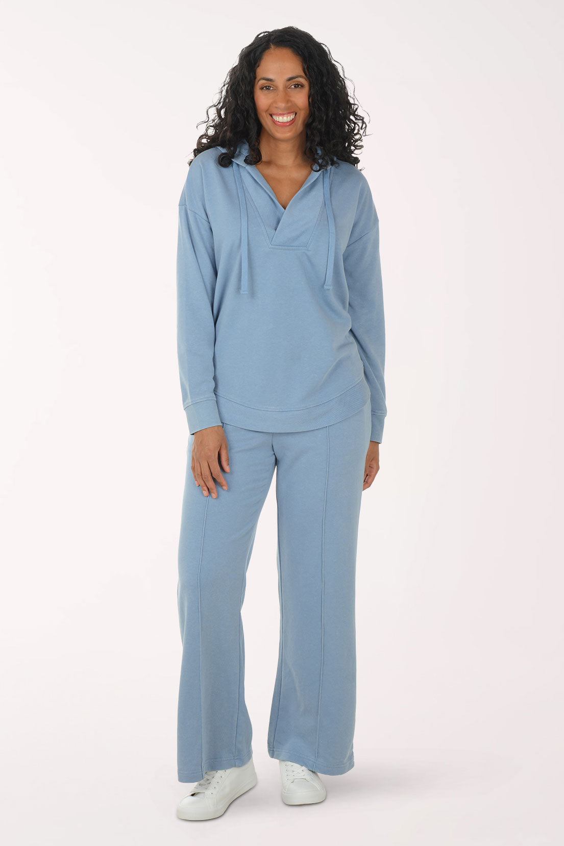 Woman wearing a light blue sweater and sweatpants set on a white background