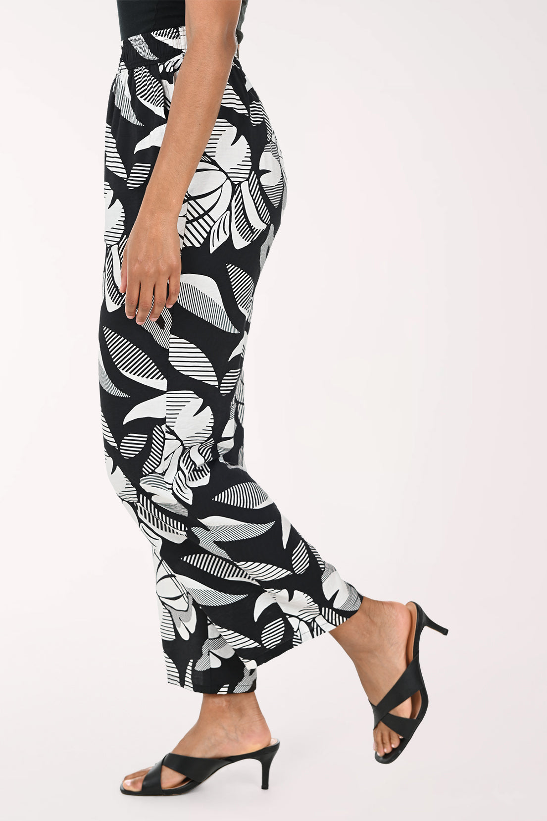 Black pants with white abstract pattern worn by a person on a white background