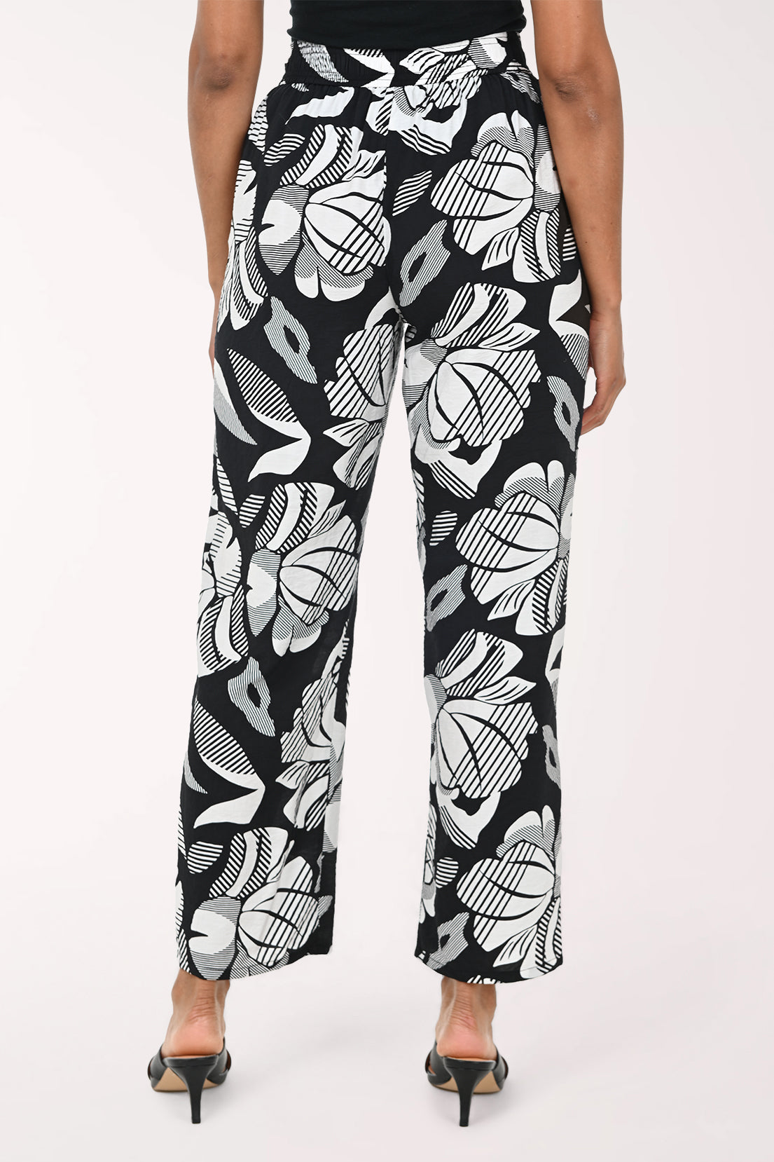 Black pants with white abstract pattern worn by a person on a white background