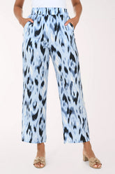 Light blue pants with black abstract pattern worn by a person on a white background