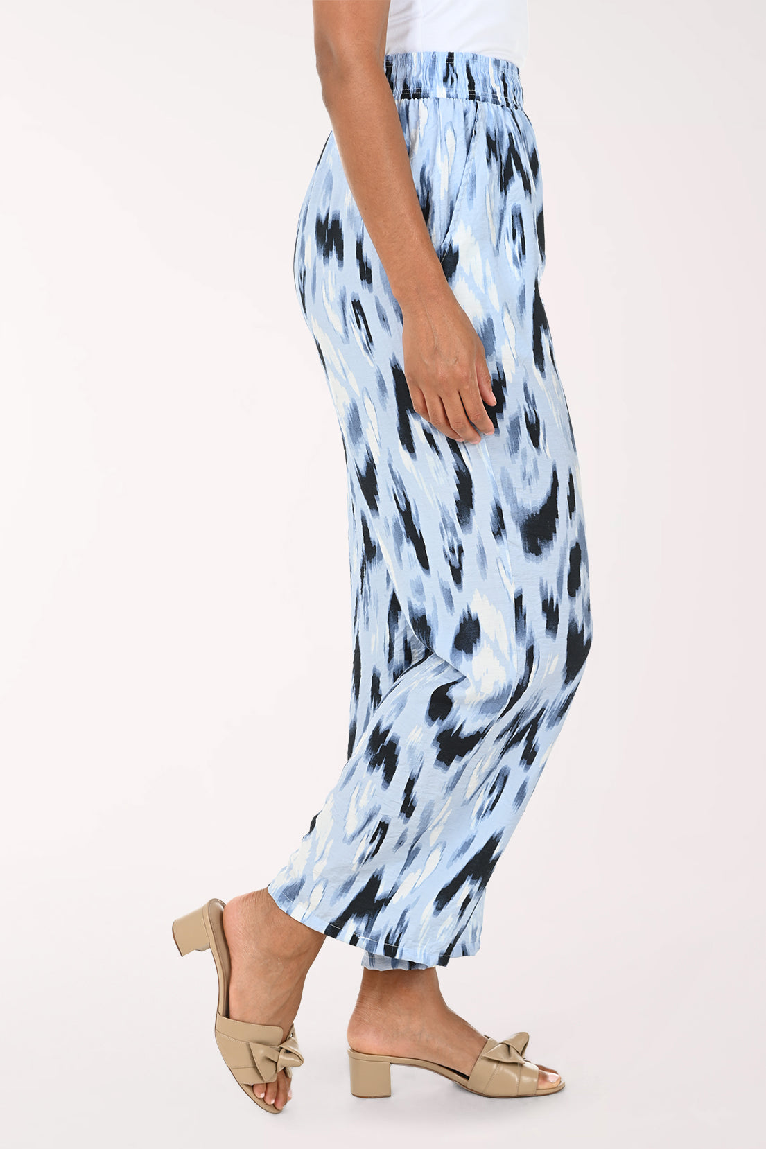 Light blue pants with black abstract pattern worn by a person on a white background
