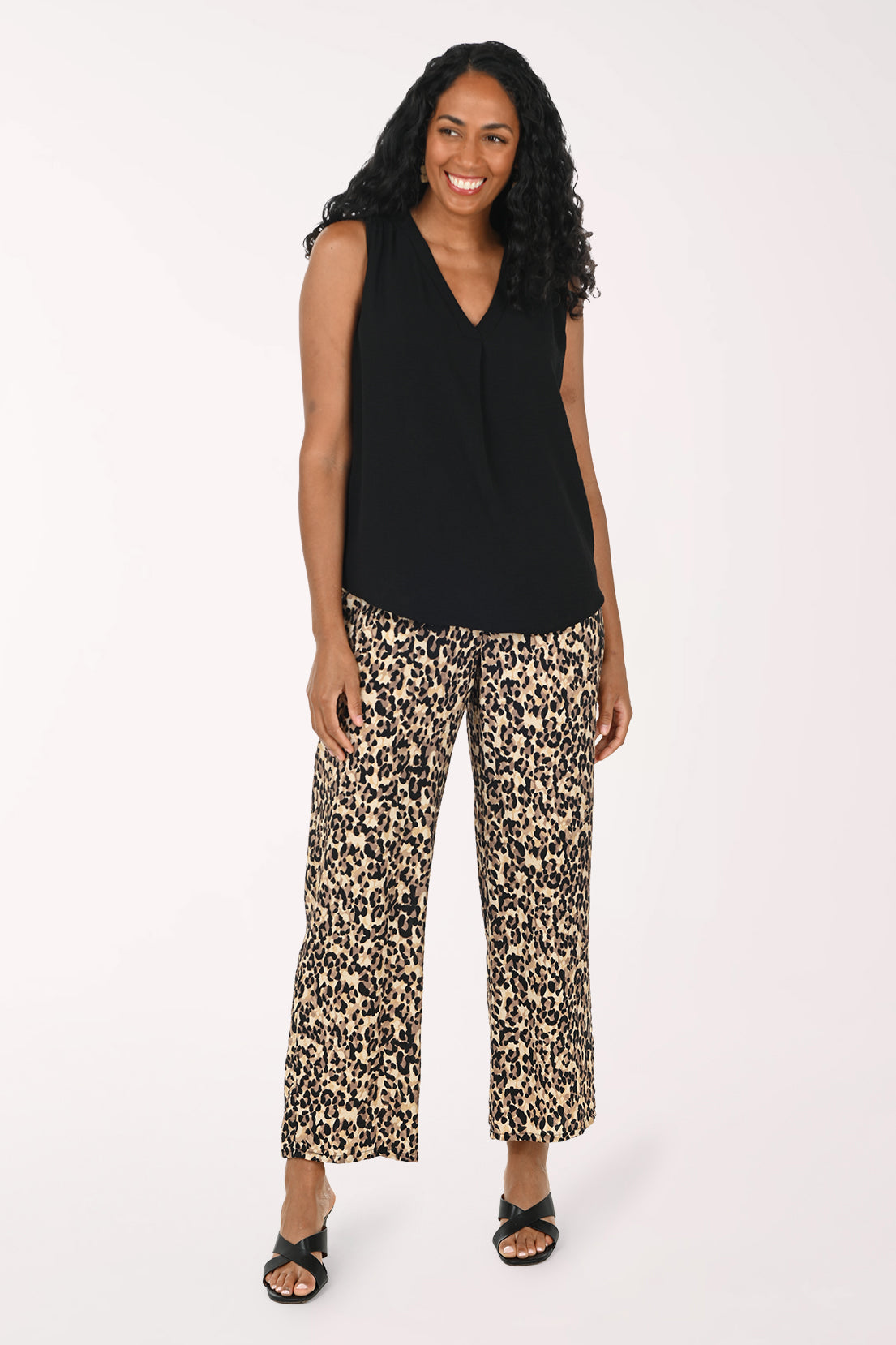 Woman wearing a black sleeveless top and patterned pants on a white background