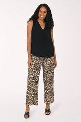 Woman wearing a black sleeveless top and patterned pants on a white background