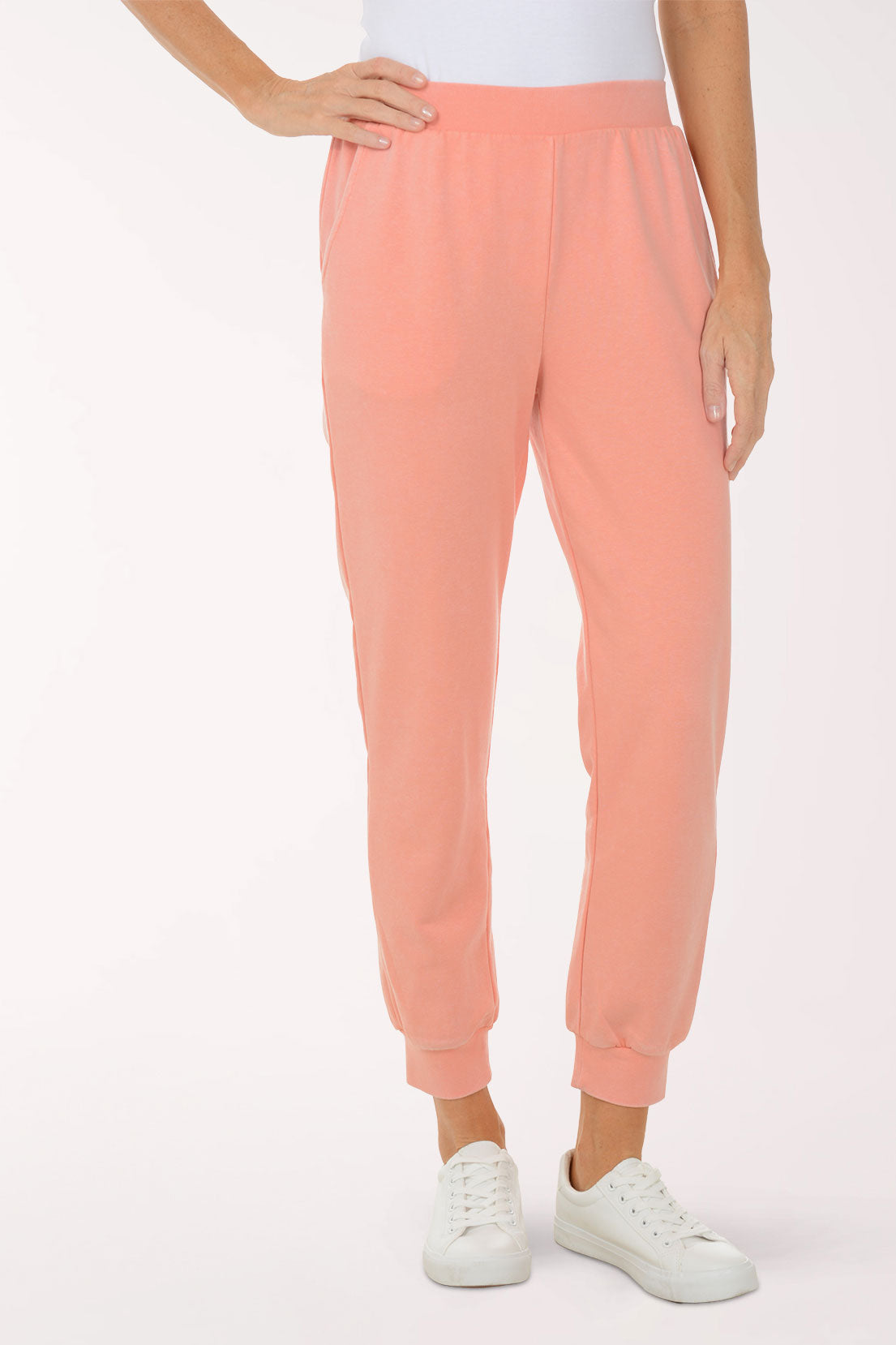 Person wearing peach-colored sweatpants on a white background