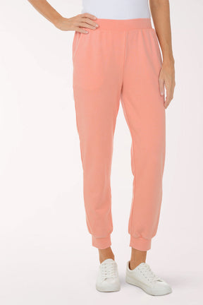 Person wearing peach-colored sweatpants on a white background