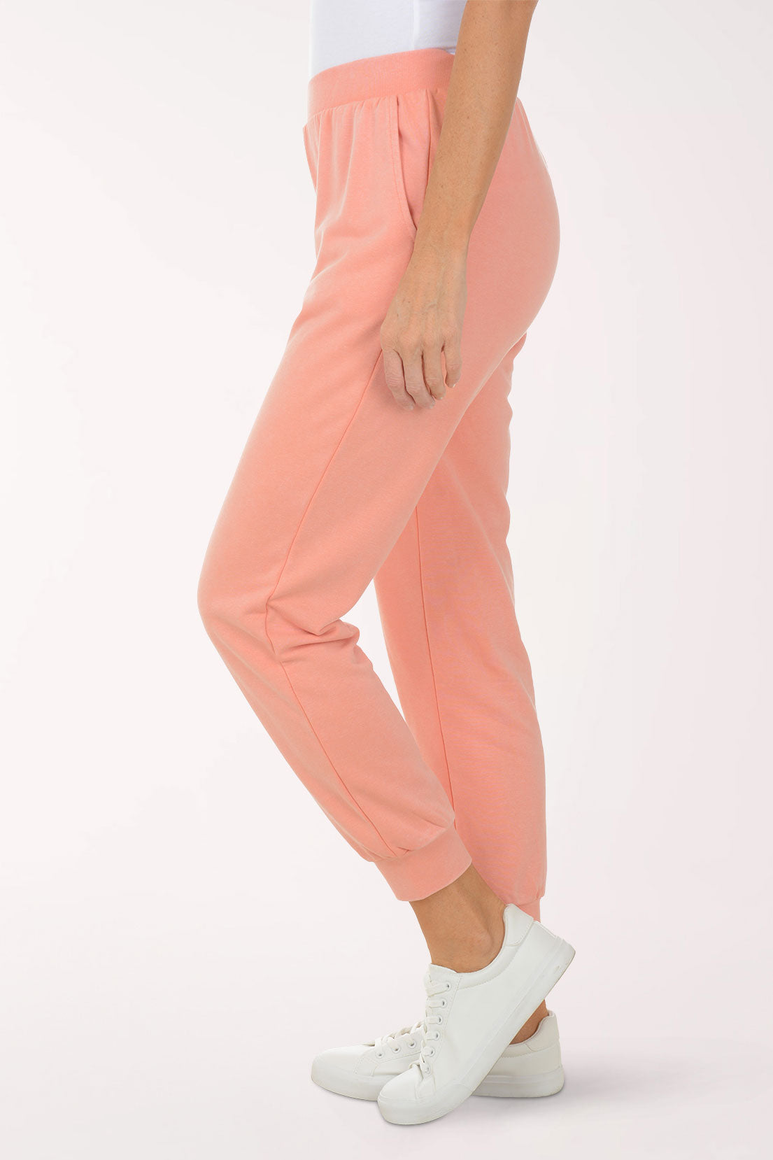 Person wearing peach-colored sweatpants on a white background