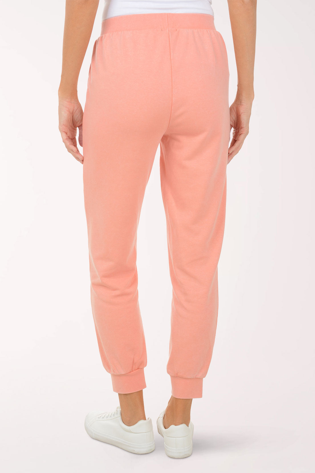 Person wearing peach-colored sweatpants on a white background
