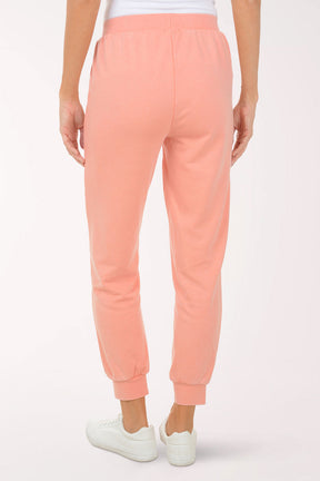 Person wearing peach-colored sweatpants on a white background