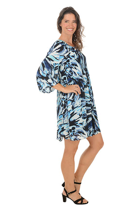 Woman wearing a blue and white patterned dress on a white background. Side shot.