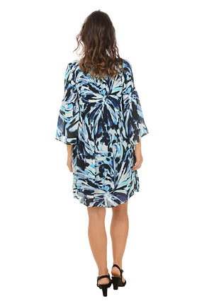 Woman wearing a blue and white patterned dress on a white background. Back shot.