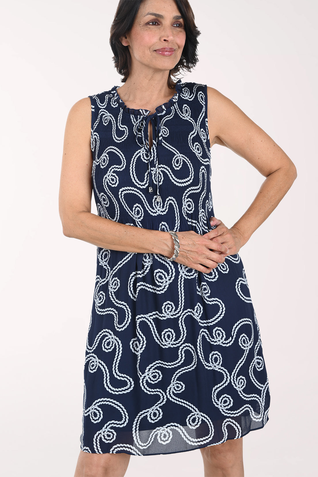 Woman wearing a navy dress with white pattern on a white background