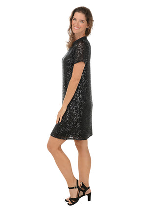 Woman wearing a black sequin dress on a white background. Side shot.