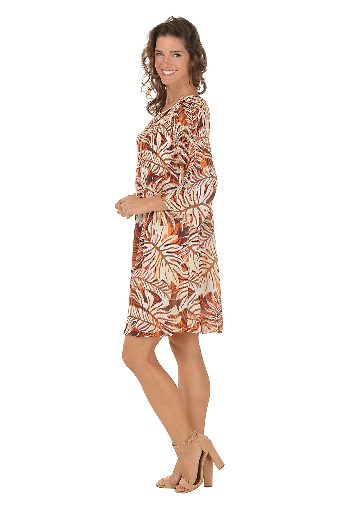 Woman wearing a patterned dress on a white background. Side shot.