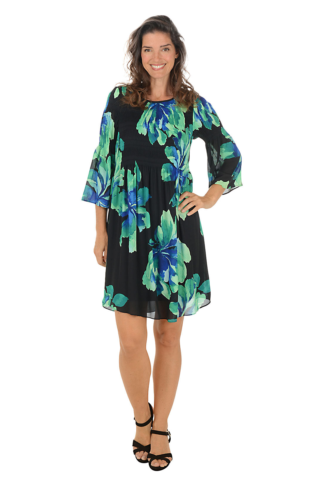 Woman wearing a black dress with blue and green floral pattern on a white background.