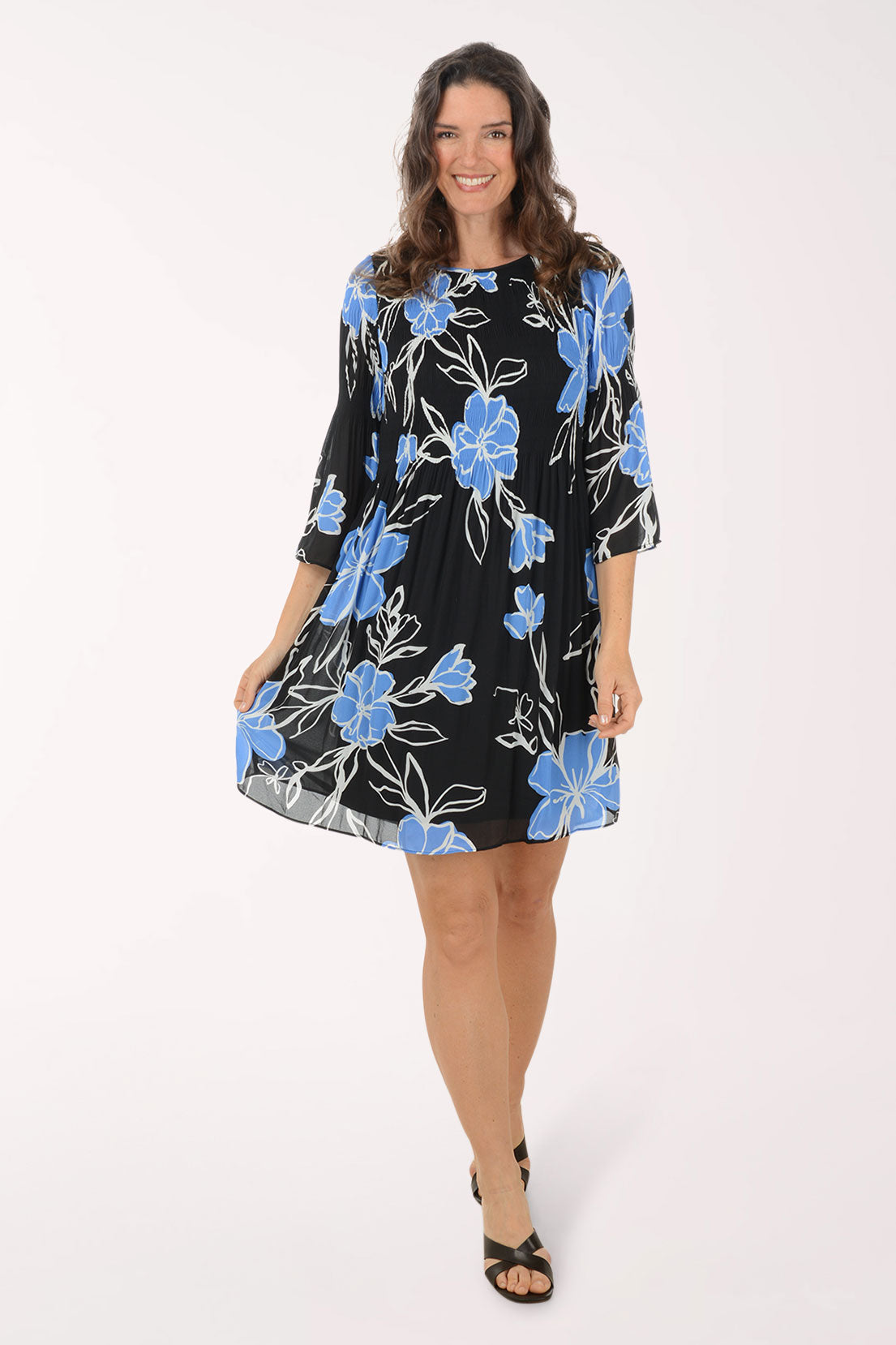 Woman wearing a black dress with blue floral patterns on a white background