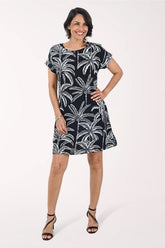 Woman wearing a black dress with white palm tree pattern on a white background