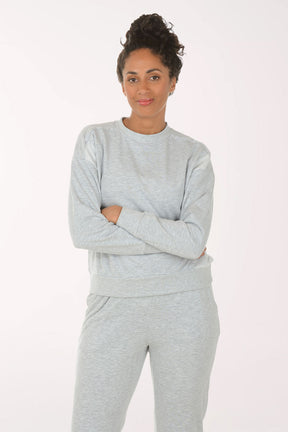 Woman wearing a gray sweatshirt and pants on a white background
