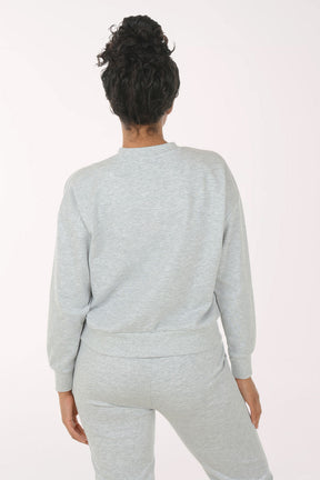 Woman wearing a gray sweatshirt and pants on a white background