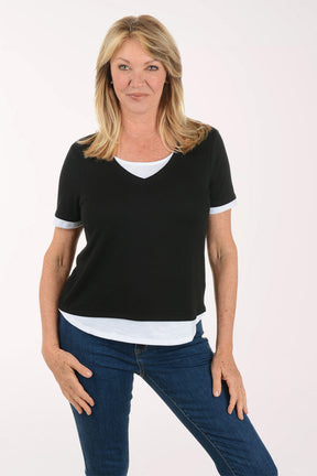 Woman wearing a black t-shirt with white trim and blue jeans on a white background