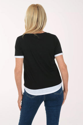 Woman wearing a black t-shirt with white trim and blue jeans on a white background