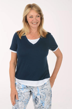 Woman wearing a navy blue top and patterned pants on a white background