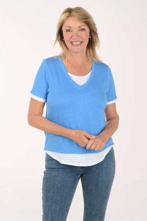Woman wearing a blue top and jeans on a white background