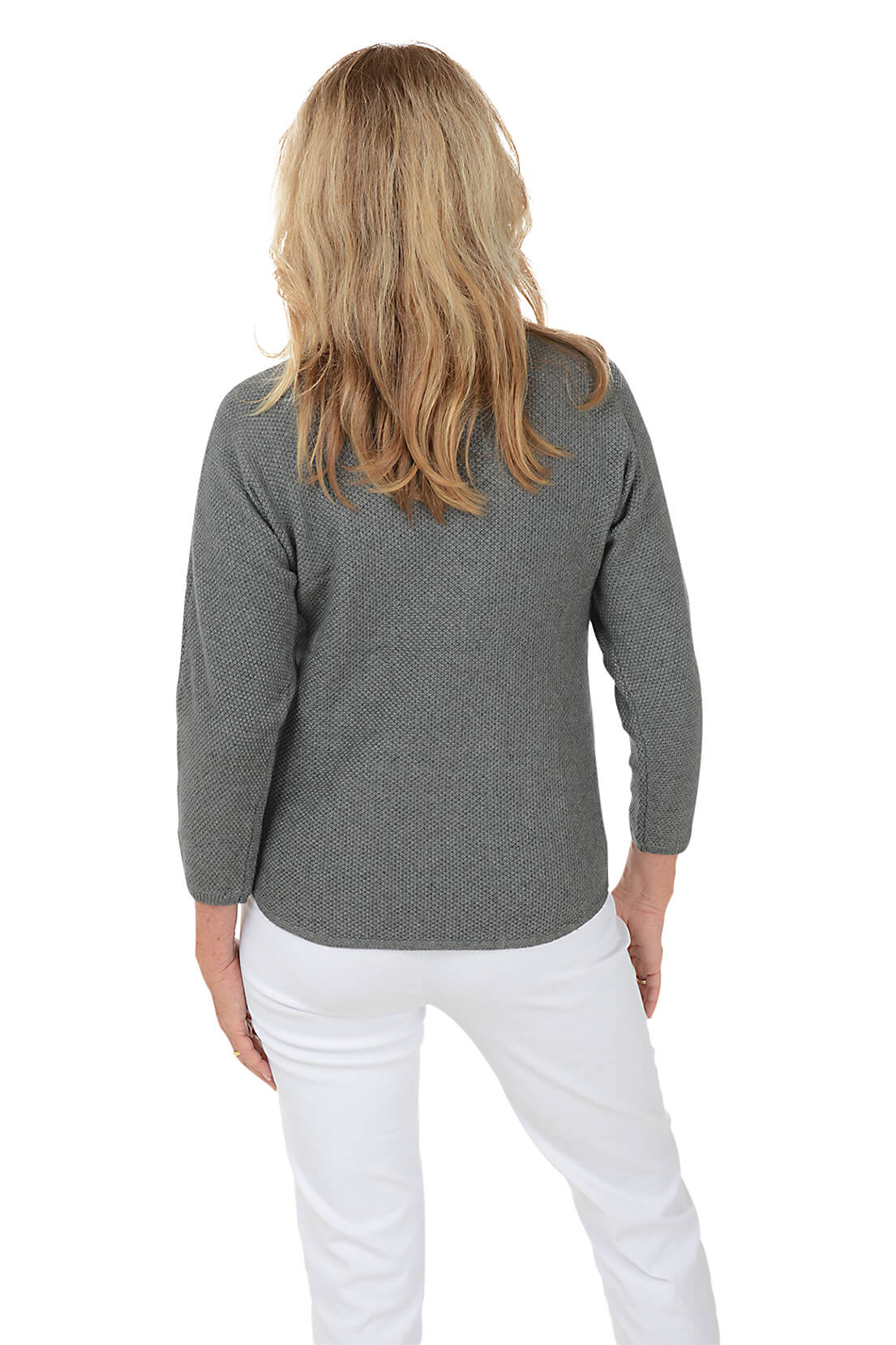 A smiling blonde woman wearing a heather gray long-sleeve top with a colorful heart outline graphic on the chest, paired with white pants, against a plain white background.