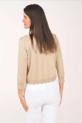 Woman wearing a beige cardigan over a white top on a white background