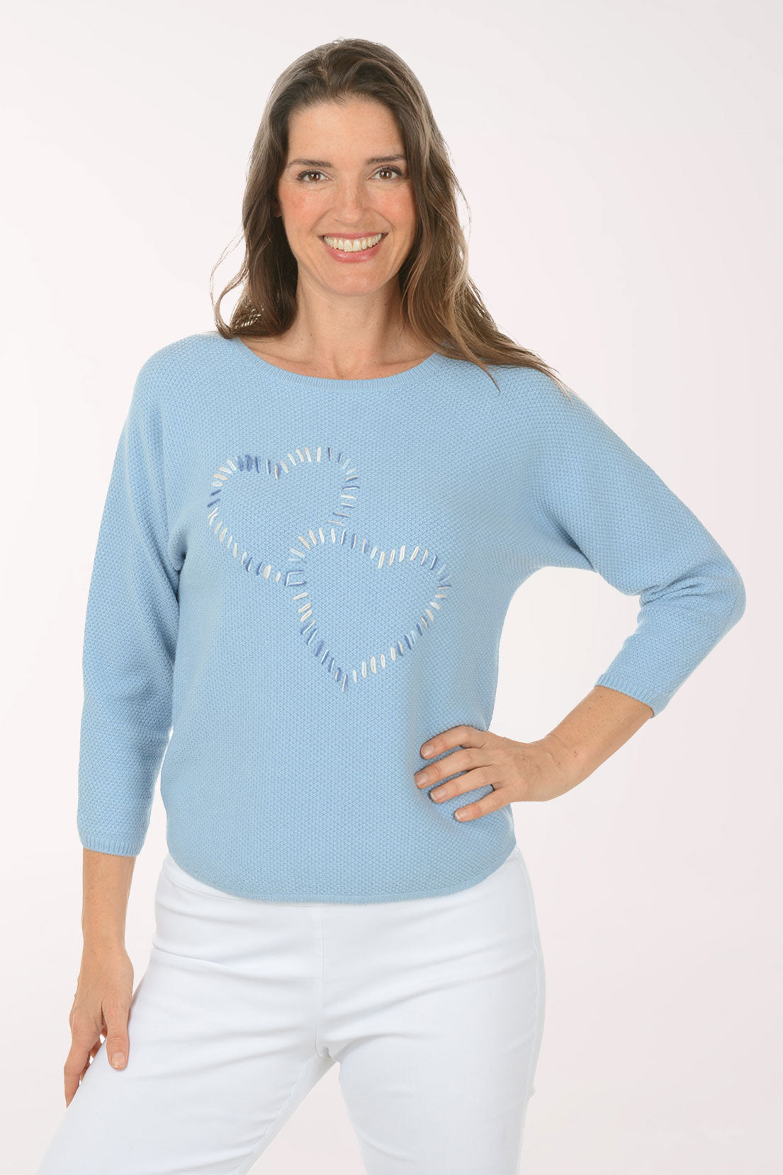 A woman wearing a blue sweater with printed hearts.