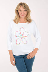 Woman wearing a white sweatshirt with a colorful daisy design on a white background