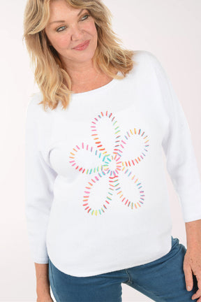 Woman wearing a white sweatshirt with a colorful daisy design on a white background. Close up