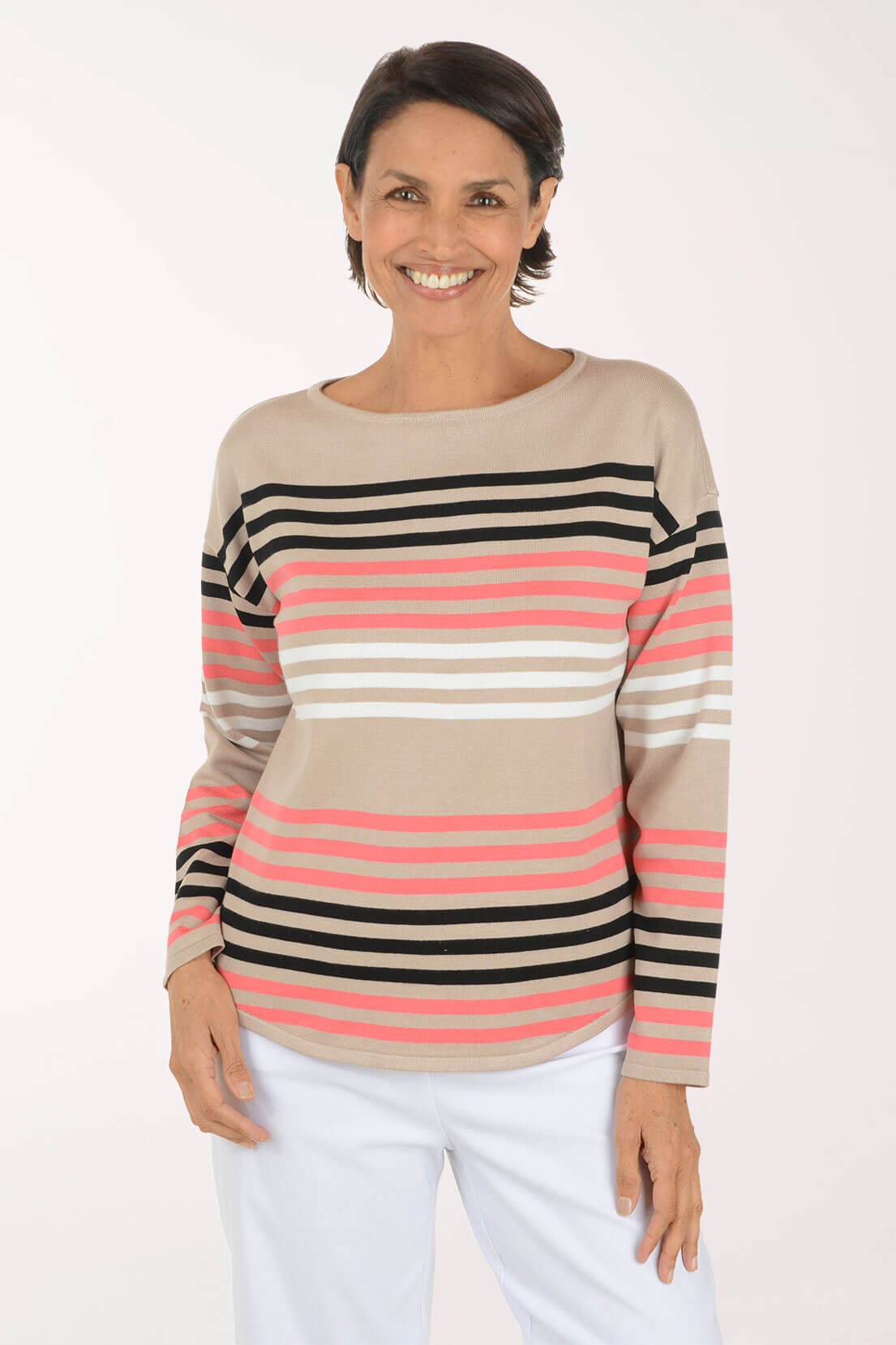 A woman wearing a beige long-sleeve knit top with horizontal stripes in black, white, and pink, paired with white pants, against a plain light background.