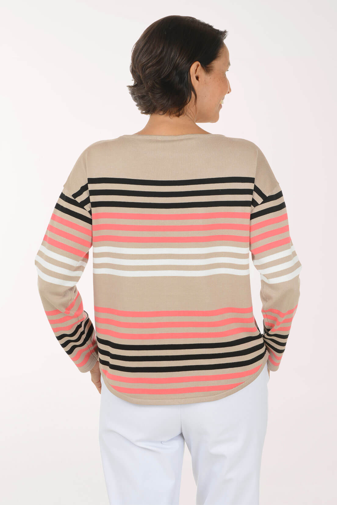 A woman viewed from the back wearing a beige long-sleeve sweater with horizontal black, white, and pink stripes, paired with white pants, against a plain white background.