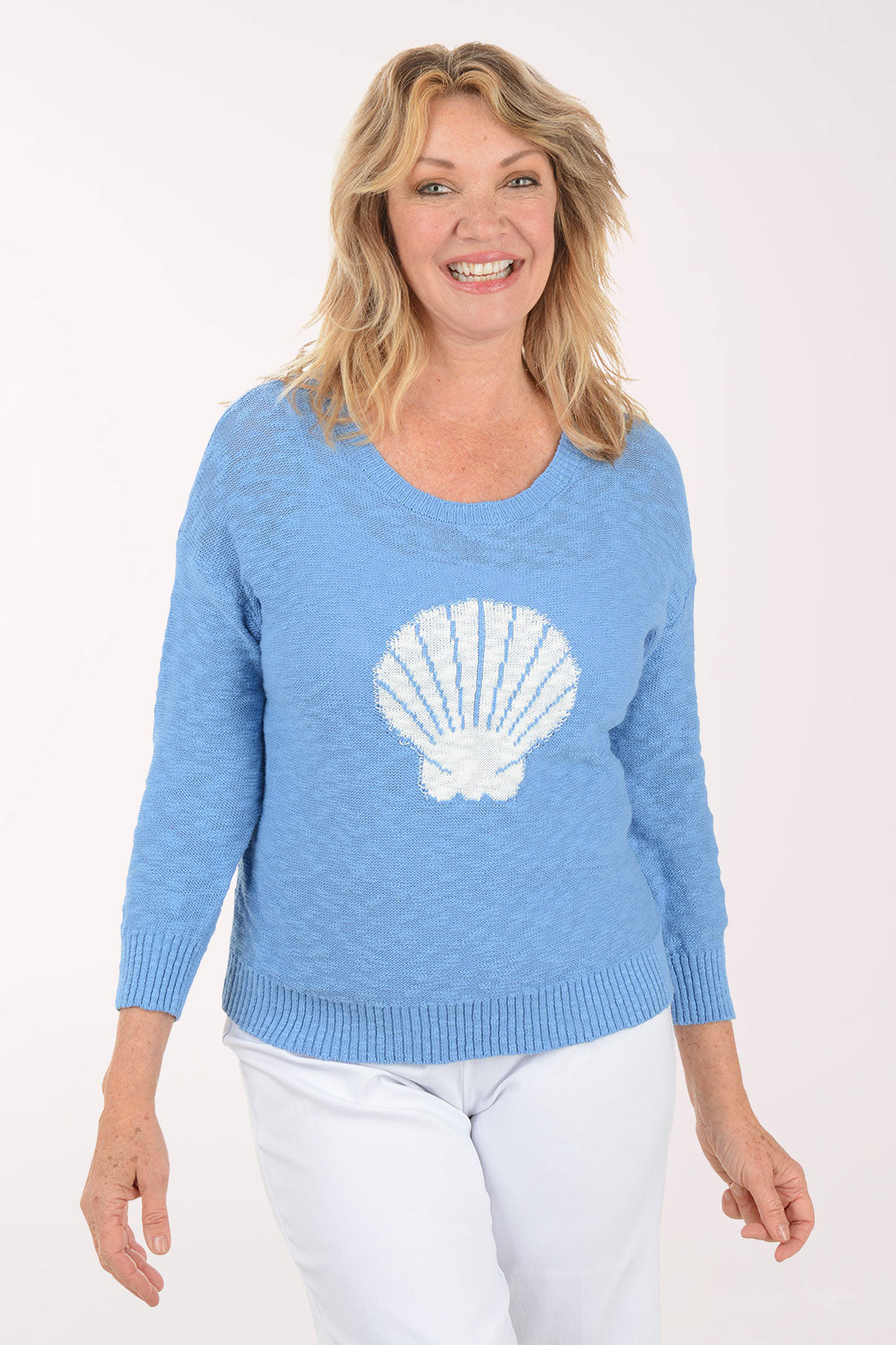 A woman wearing a blue sweater with a printed seashell.