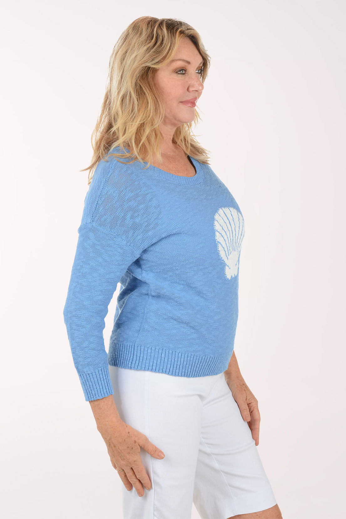 A woman wearing a blue sweater with a printed seashell.