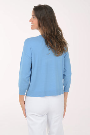 Woman wearing a light blue sweater with a white floral design on a white background