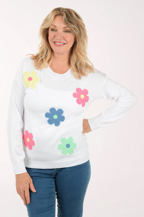 A woman wearing a white sweater with flowers.