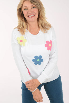 A woman wearing a white sweater with flowers.