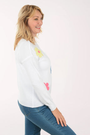 A woman wearing a white sweater with flowers.