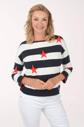 Woman wearing a striped sweater with red stars and white pants on a white background