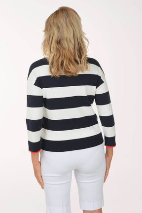 Woman wearing a navy and white striped sweater with white pants on a white background