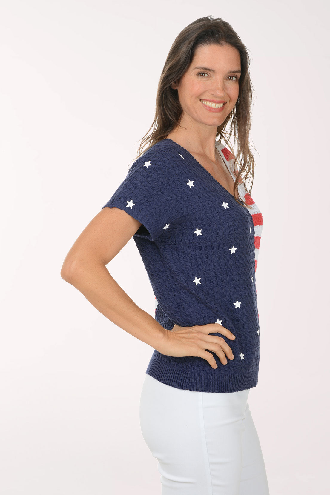 Woman wearing a colorful short-sleeve top with a pattern resembling the American flag on a white background