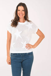 Woman wearing a white star-patterned sweater and blue jeans on a white background